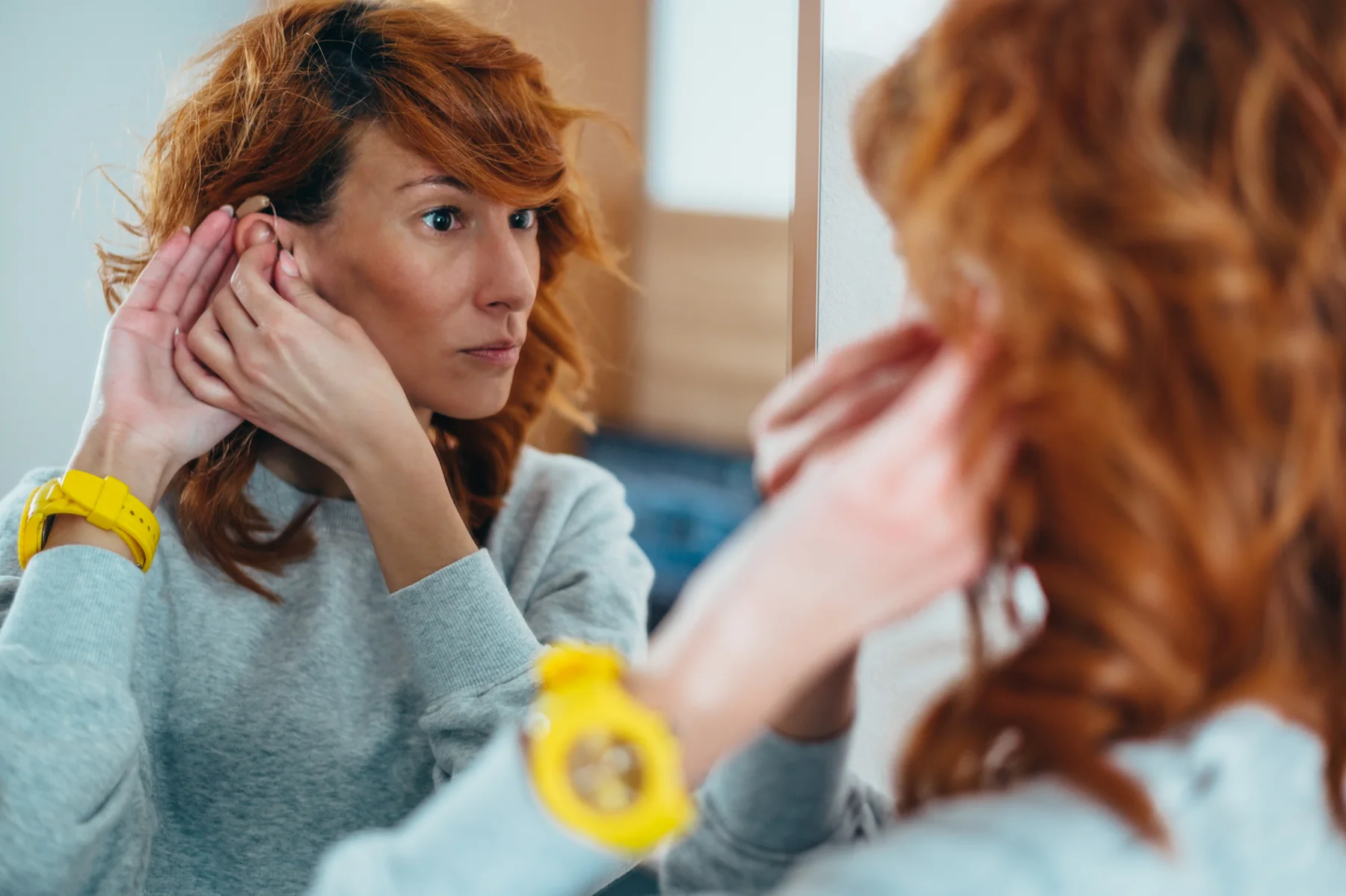 Person holding an ear while noticing tinnitus symptoms